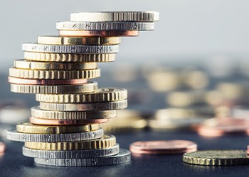 An uneven stack of coins standing tall among other scattered coins