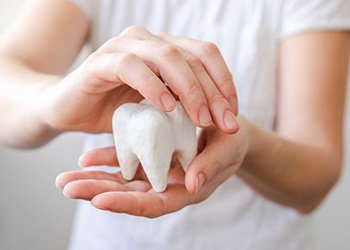 Individual holding a giant model tooth