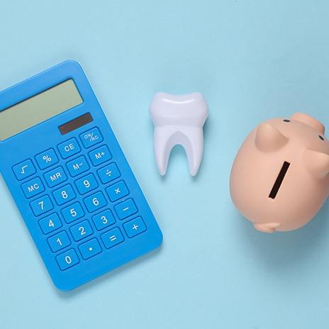 A calculator, false tooth, and piggy bank against a blue background