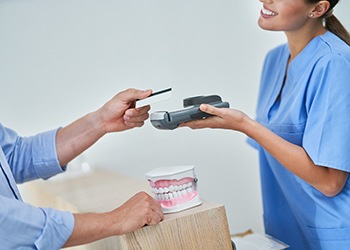 A man using a credit card to pay the cost of CEREC dental crowns