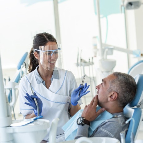 Smiling dentist talking to patient with toothache