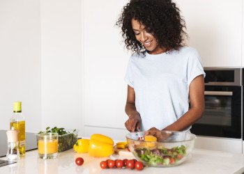 Woman smiling while preparing salad in kitchen