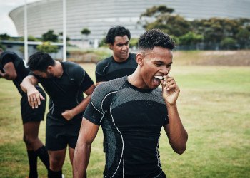 Man putting on mouthguard while stepping onto field