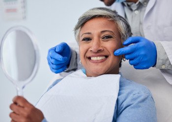 Woman smiling while holding handheld mirror