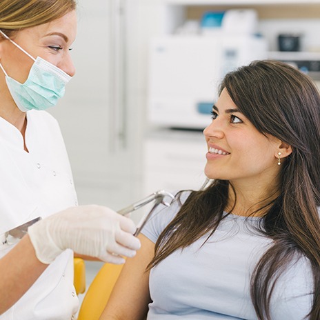 Dentist holding forceps while talking to patient