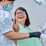 Woman smiling with dentist while reviewing X-ray