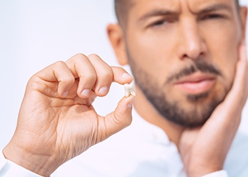 Frowning man holding his extracted tooth